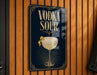A sign with the text "VODKA SOUR" and an illustration of a cocktail glass with a lemon peel.