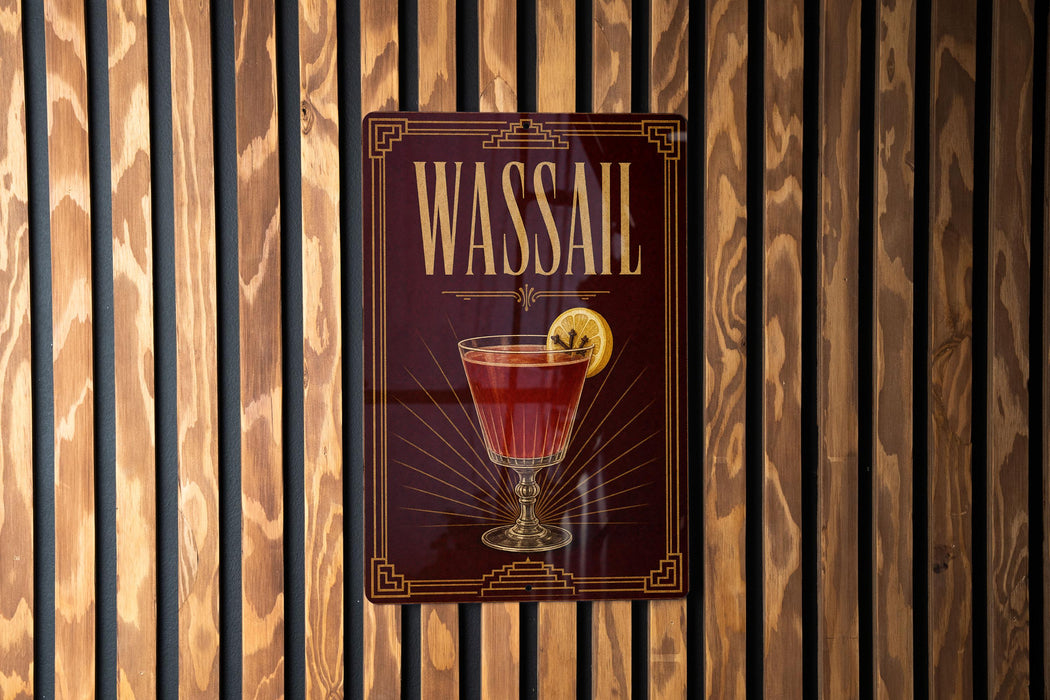 A metallic sign with the word "WASSail" on it, featuring an illustration of a cocktail glass with a lemon slice.