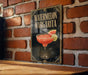 A sign for a "Watermelon Margarita" cocktail is displayed on a brick wall.