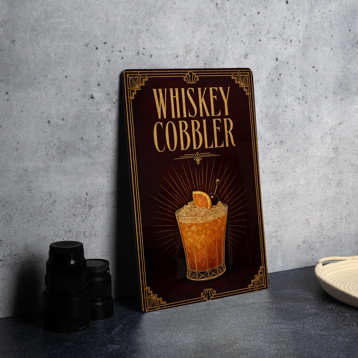 A framed illustration of a whiskey cobbller cocktail is displayed on a dark background, with a stack of black camera lenses and a white dish visible to the side.