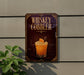 A sign for a whiskey cobbler cocktail is displayed on a wall, with a glass of the cocktail and an orange slice as the main visual elements.