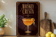 a decorative sign with the text "Whiskey Crusta" and an illustration of a glass of whiskey with a lemon twist.