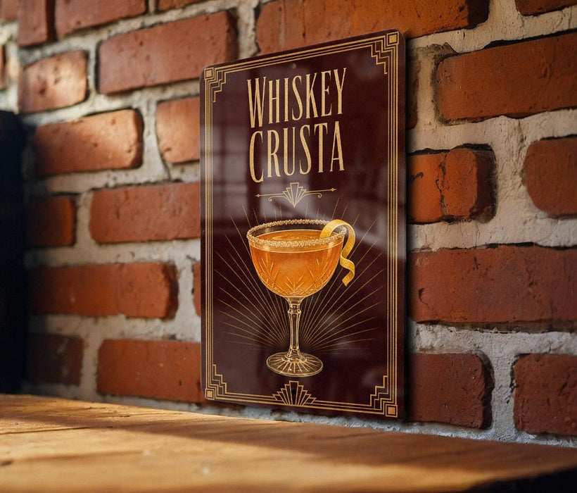 A framed poster of a whiskey cocktail is displayed on a brick wall, featuring an illustration of a glass with a cocktail inside.
