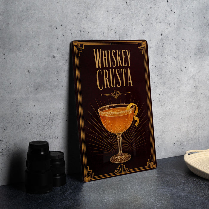 A framed poster or sign with the title "Whiskey Crusta" and an illustration of a whiskey glass with a lemon twist.