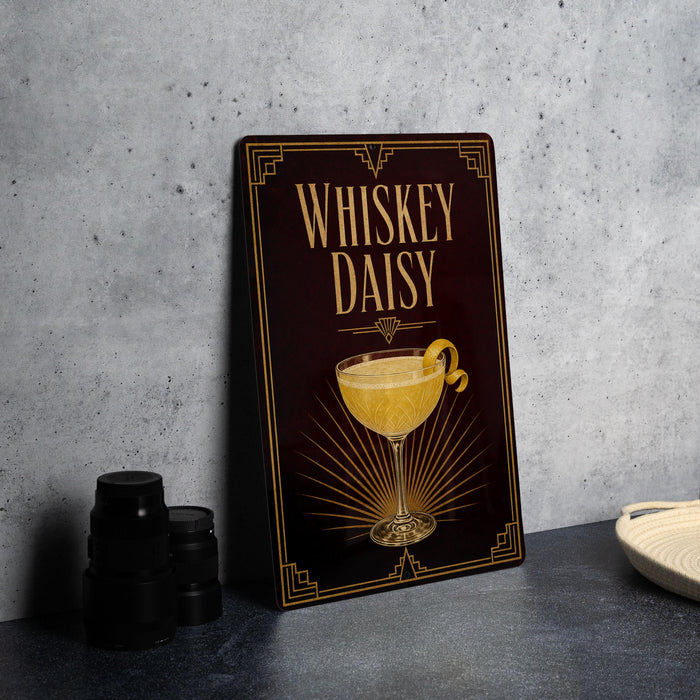 A framed poster of a whiskey daisy cocktail is displayed on a wall, accompanied by a stack of black camera lenses and a white dish.