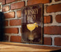 A sign with the text "Whiskey Daisy" and an illustration of a cocktail glass is displayed on a brick wall.