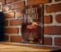 A sign for whiskey Sangaree is displayed on a brick wall, featuring an illustration of a glass containing a red-colored drink with a cherry on top.