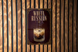 a poster advertising a drink called "White Russian" with a glass of the drink and ice cubes.