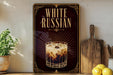 A framed advertisement for "White Russian" on a wall, featuring an illustration of a glass of the cocktail.
