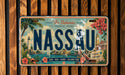 A vintage-style license plate with the text "The Bahamas" and "NASSAU" prominently displayed, along with various tropical elements such as palm trees, flowers, and a beach scene.