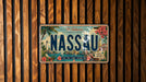 A vintage license plate from Nassau, Bahamas, with a tropical island scene and text indicating the location.
