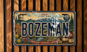 A vintage Montana license plate with a mountain landscape and various landmarks, including a water tower, buildings, and a moose.
