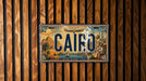 A license plate with the word "CAIRO" printed on it, mounted on a wooden wall.