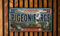 A vintage-style license plate for Tennessee, featuring the name "Pigeon Forge" and the location "The Smoky Mountain Country".