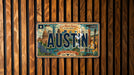 A vintage license plate from Austin, Texas, with the text "Live Music Capital of the World" and "Keep Austin Weird" printed on it, displayed on a wooden wall.