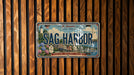 A vintage license plate from New York, with the text "Sag Harbor" prominently displayed, is mounted on a wooden wall.