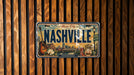 A vintage license plate from Tennessee, featuring an illustration of Nashville and its landmarks, is displayed on a wooden wall.