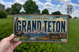 A vintage license plate from Grand Teton National Park, featuring a scenic mountain landscape and wildlife.
