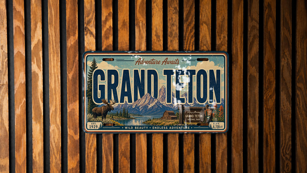 A vintage license plate from Grand Teton, with a scenic mountain landscape and moose illustration, is displayed on a wooden wall.