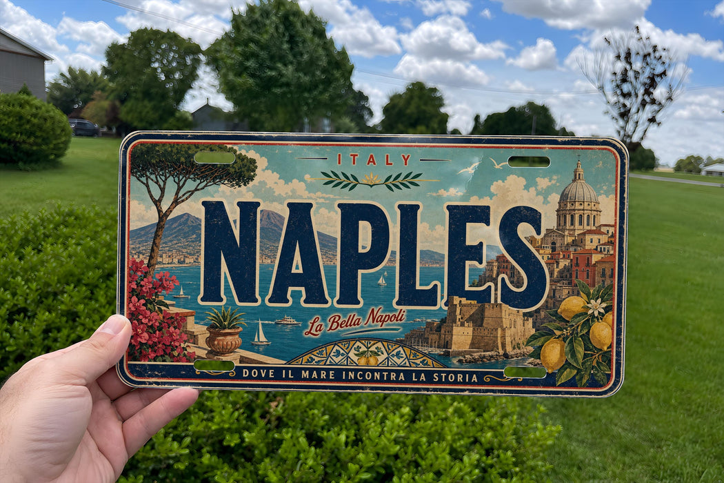 A person is holding a license plate with the word "NAPLES" prominently displayed on it. The license plate also features an illustration of a cityscape and a body of water, along with the text "ITALY" and "La Bella Napoli".