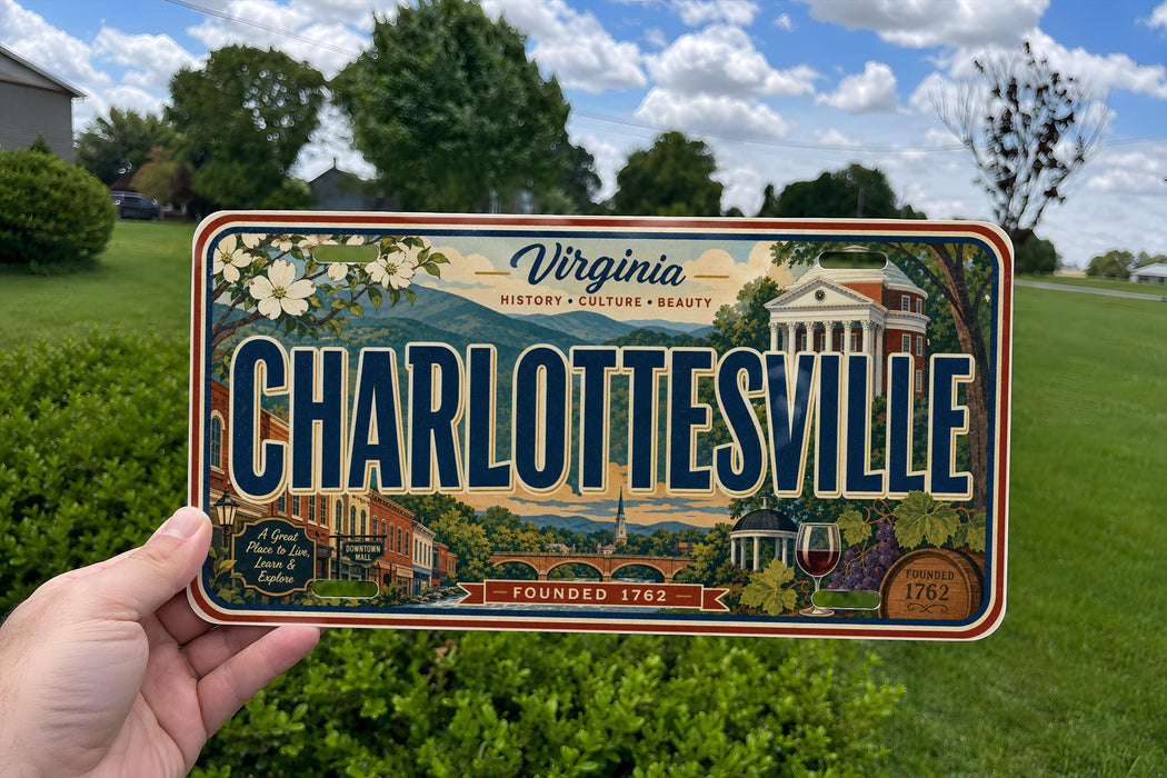 A person is holding a Virginia license plate that says "CHARLOTTSVILLE" with a scenic background of buildings, trees, and a river.