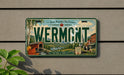 A vintage license plate from Vermont with a scenic landscape and text that reads "Wermont" and "Green Mountains, Pure Vermont".