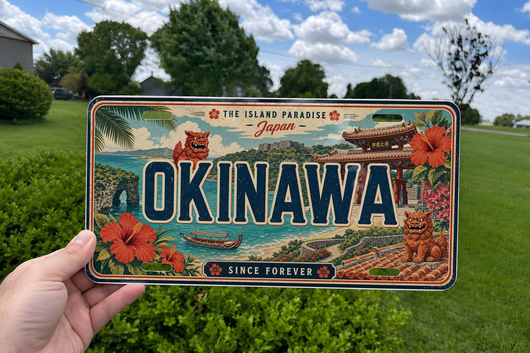 A person is holding a license plate with the word "OKINAWA" prominently displayed, surrounded by various scenic elements such as flowers, a bridge, and a body of water.