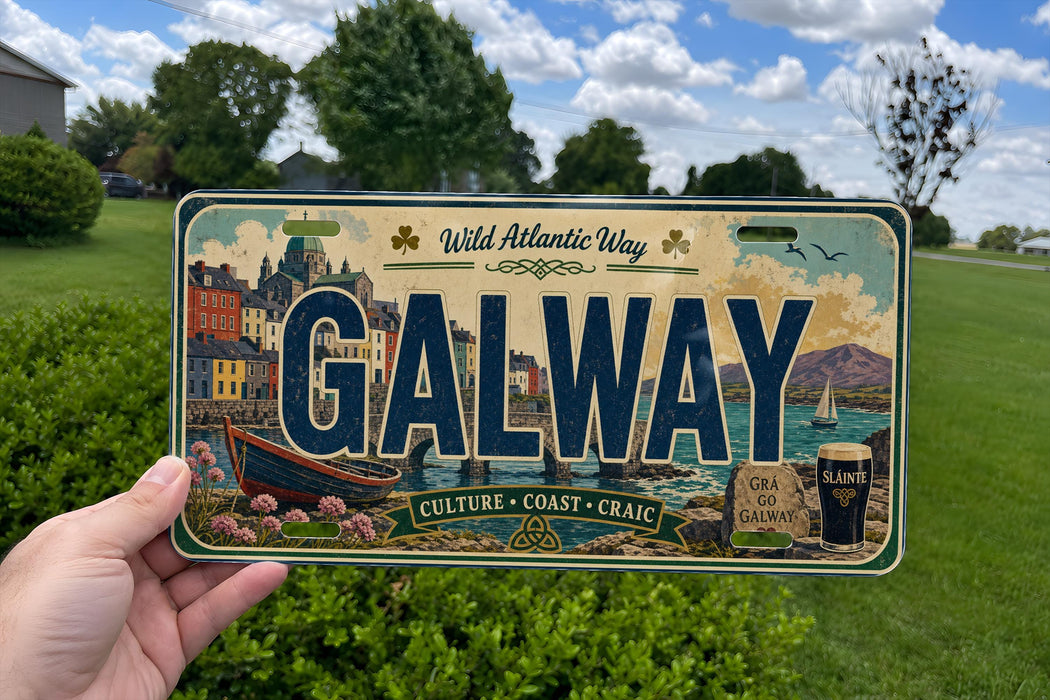 A person is holding a license plate with the word "GALWAY" prominently displayed on it. The license plate also features illustrations of a cityscape, a boat, and a glass of beer, along with the text "Wild Atlantic Way" and "Culture - Coast - Craig".