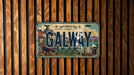 A vintage license plate with the word "GALWAY" printed on it, set against a wooden background.