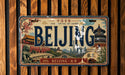 A vintage license plate from China with the word "Beijing" prominently displayed, featuring various landmarks and scenes from the city.