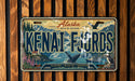 A license plate with the text "KENAI F. JORD" and an illustration of a scenic landscape with mountains, a lake, and wildlife.