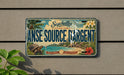 A vintage license plate from Seychelles, featuring a tropical beach scene with palm trees, a blue sky, and a large ocean.
