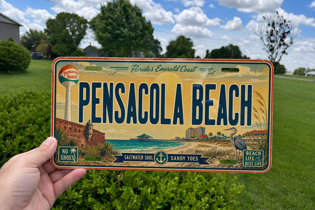 A person is holding a license plate from Pensacola Beach, Florida, which features a beach scene and the text "Pensacola Beach" prominently displayed.