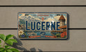 A license plate with the word "LUCERNE" prominently displayed, featuring a scenic mountain landscape and a castle-like structure.