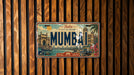 A vintage license plate from India, featuring the city of Mumbai, is displayed against a wooden background.