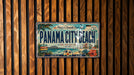 A vintage license plate from Panama City Beach, Florida, with a tropical beach scene and palm trees.