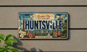 A license plate from Alabama that reads "HUNTSVILLE" with various landmarks and symbols from the state, such as the Space Shuttle launchpad and the state building.