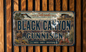 A license plate with the text "Black Canyon of the Gunnison" and an illustration of a mountain landscape with a bird in flight.