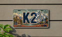 A license plate with the word "K2" prominently displayed, featuring a mountain landscape and other scenic elements.