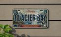 A vintage Alaska license plate with the text "Glacier Bay" and a scenic image of the bay with mountains in the background.