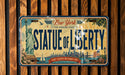A vintage-style license plate with the text "New York Statue of Liberty" and an illustration of the Statue of Liberty.