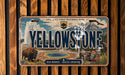 A vintage license plate with the text "YELLOWSTONE" and an illustration of a buffalo, a geyser, and a mountain range.