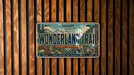 A license plate with a scenic mountain landscape and the text "Wonderland Trail" on it, mounted on a wooden wall.