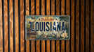 A license plate from Louisiana, featuring a vintage design with a boat, flowers, and buildings.