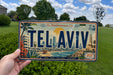 A person is holding a license plate with the word "TELAVIV" on it, which is a city license plate from Tel Aviv, Israel.