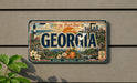 A vintage Georgia license plate with a scenic illustration of the state's landmarks and natural beauty.